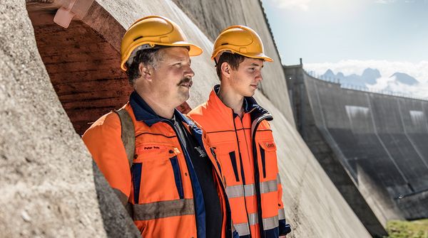 Zwei Mitarbeitende stehen vor dem Abgrund vom Staudamm